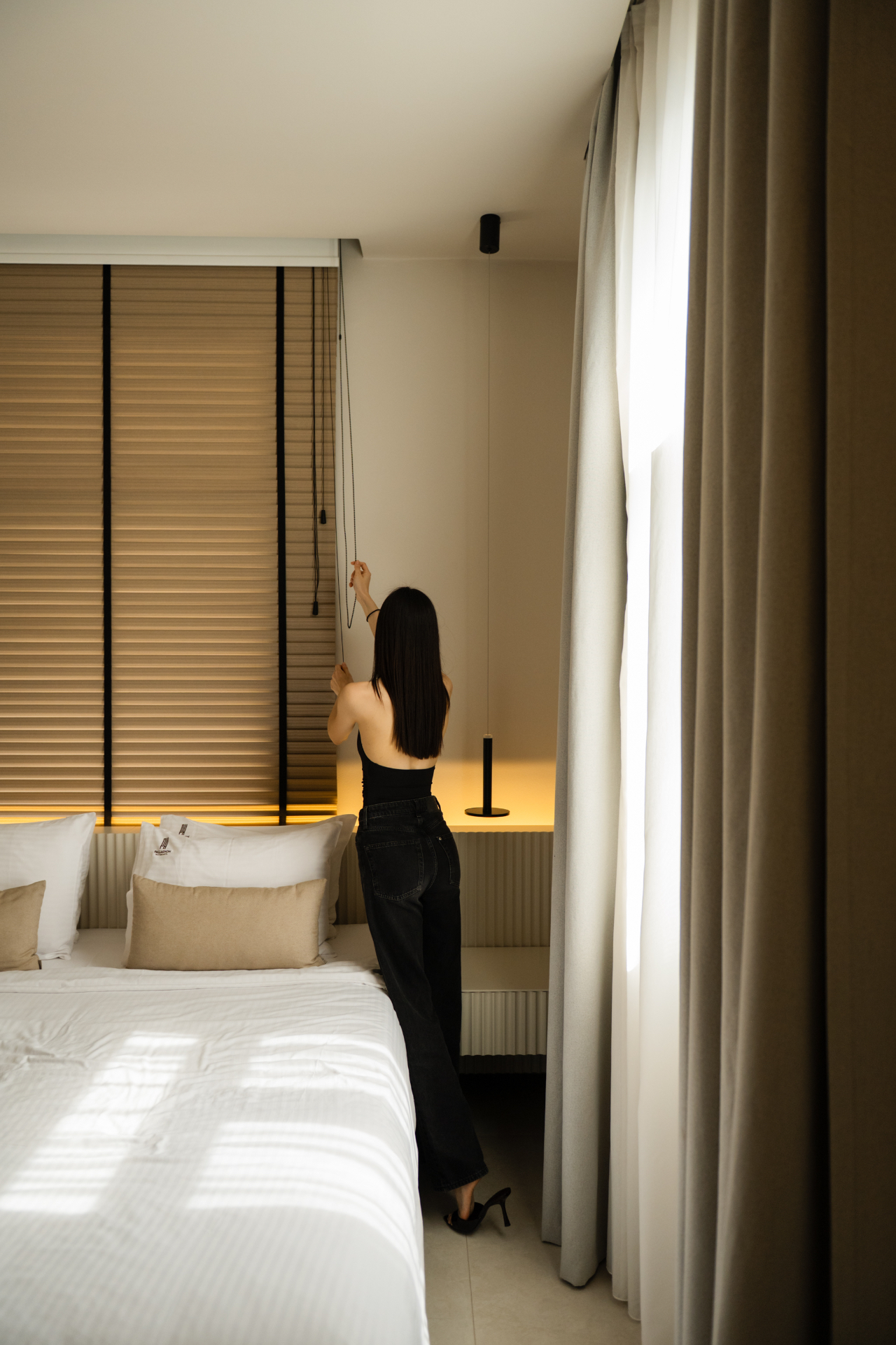 Deluxe Room with Extra Bed — adjusting the wooden blinds by the bed